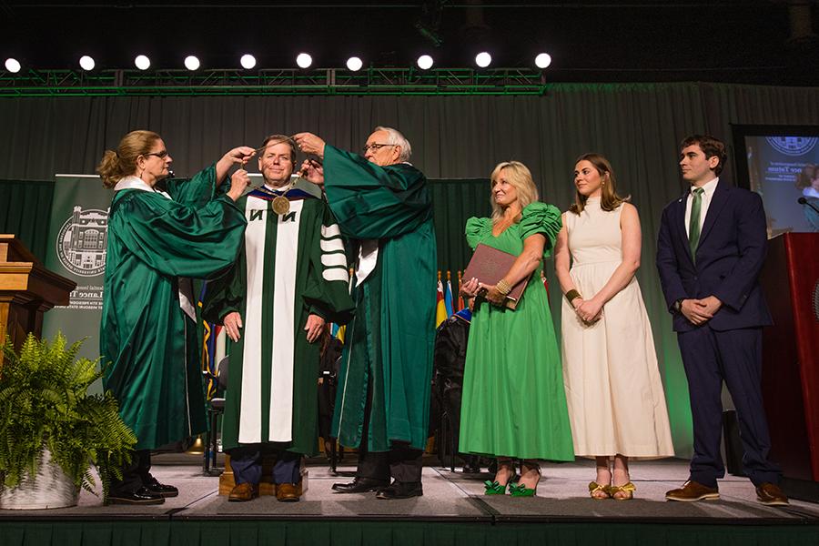 Northwest Regents Mel Tjeerdsma 和 Roxanna Swaney placed the University's chain of office on Dr. 兰斯·塔图姆的肩膀，他的家人在一旁看着. (Photo by Lauren Adams/<a href='http://myce.ospifse.net'>网上赌博网站十大排行</a>)